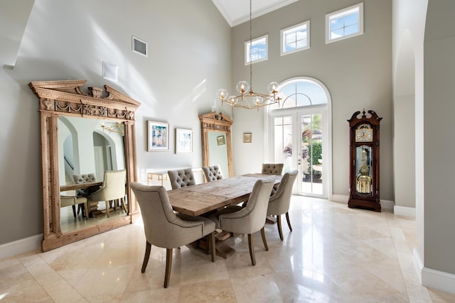 dining room with a chandelier, french doors, ornamental molding, and a towering ceiling