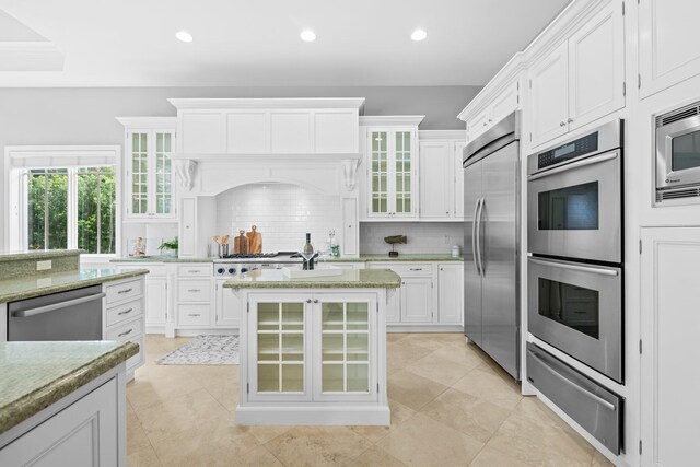 475 NE 4th St, Boca Raton, FL 33432 - kitchen featuring built in appliances, a warming drawer, tasteful backsplash, white cabinetry, and light stone countertops