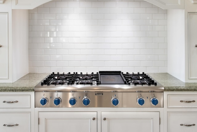 kitchen with white cabinets, decorative backsplash, and stainless steel gas stovetop