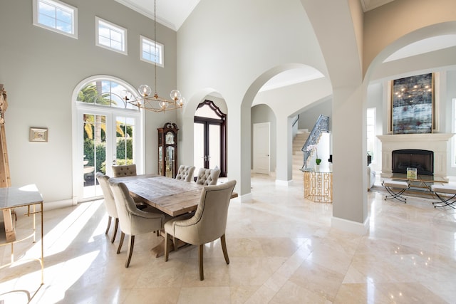 dining space featuring french doors, crown molding, a chandelier, and a high ceiling