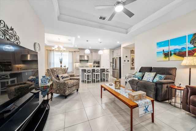 9597 SW Royal Poinciana Dr, Port Saint Lucie, FL 34987 - tiled living room featuring ornamental molding, ceiling fan with notable chandelier, and a tray ceiling