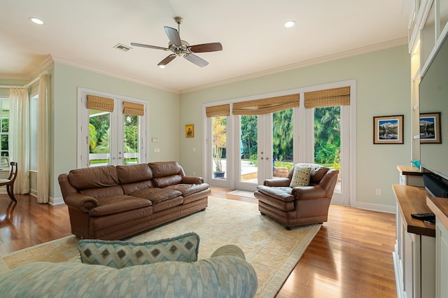 living room with ornamental molding, french doors, a healthy amount of sunlight, and light wood-type flooring