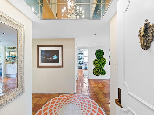 hallway with dark tile patterned floors and an inviting chandelier