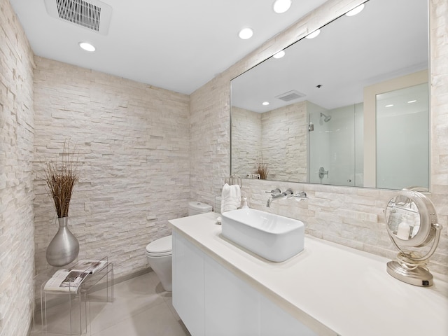 bathroom with toilet, tile walls, vanity, a shower with door, and tile patterned flooring