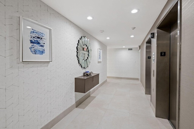 corridor featuring elevator and light tile patterned floors