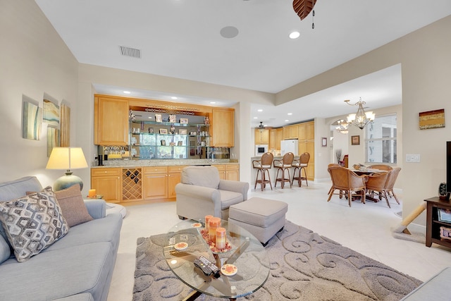 living room with indoor bar and ceiling fan with notable chandelier