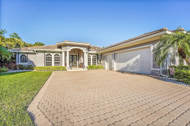 mediterranean / spanish house featuring a garage and a front lawn