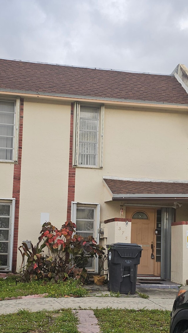 view of front of property featuring roof with shingles and stucco siding