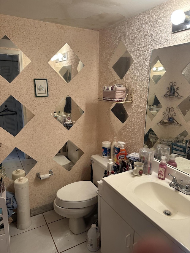 half bathroom with vanity, tile patterned flooring, toilet, and wallpapered walls