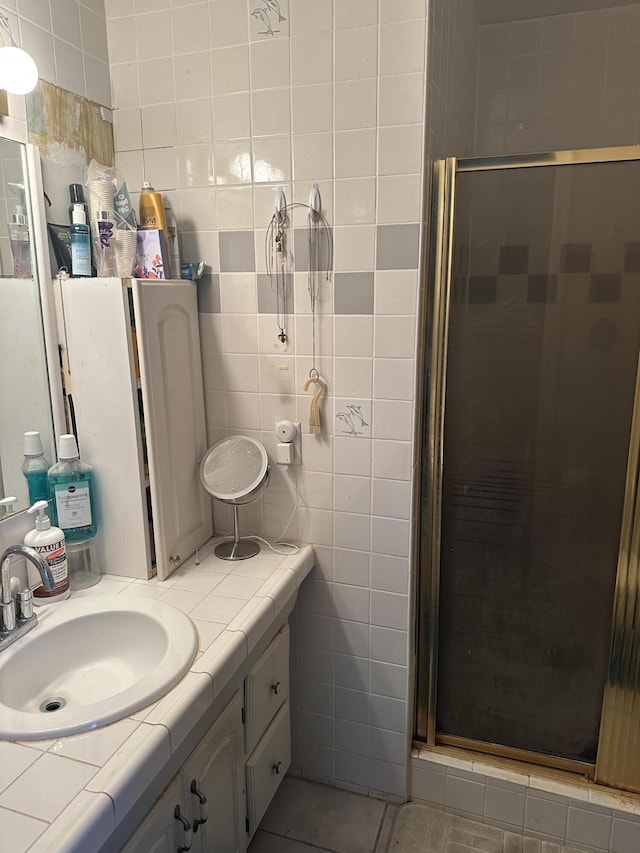 bathroom with a stall shower, tile patterned floors, tile walls, and vanity