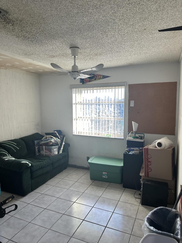 living area with light tile patterned floors, ceiling fan, and a textured ceiling