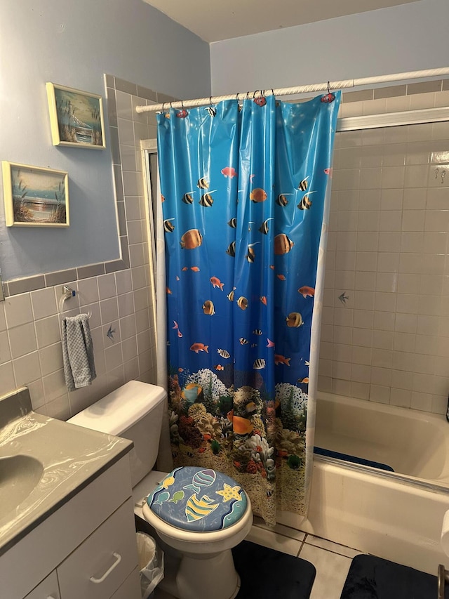 bathroom with tile walls, shower / bathtub combination with curtain, toilet, vanity, and tile patterned floors