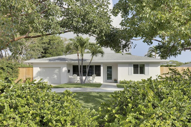 ranch-style house with stucco siding, an attached garage, a front lawn, and fence