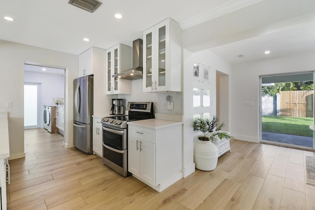 kitchen featuring visible vents, washer / clothes dryer, appliances with stainless steel finishes, wall chimney exhaust hood, and light countertops