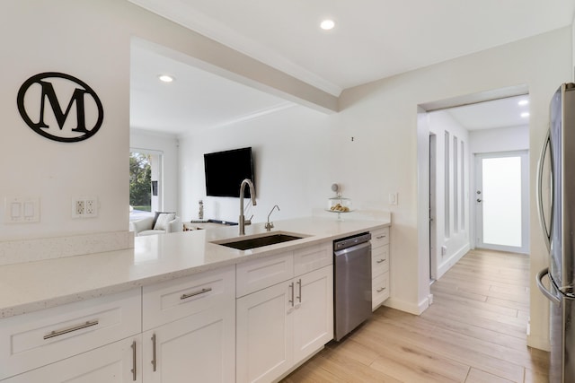 kitchen with light stone counters, a sink, light wood-style floors, appliances with stainless steel finishes, and white cabinetry