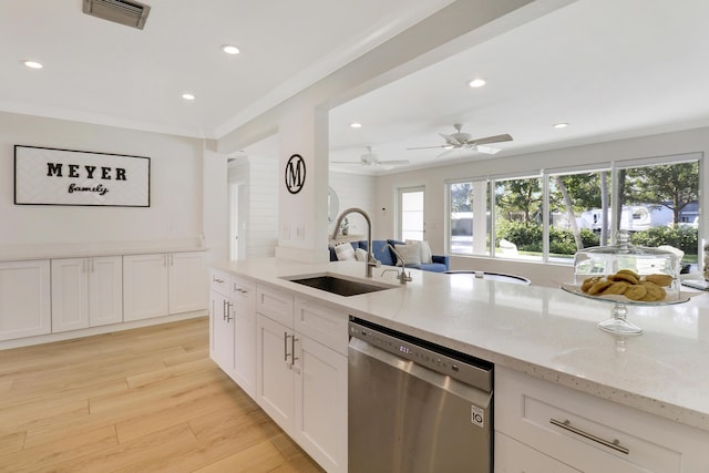 kitchen with visible vents, light stone counters, light wood-style flooring, stainless steel dishwasher, and a sink