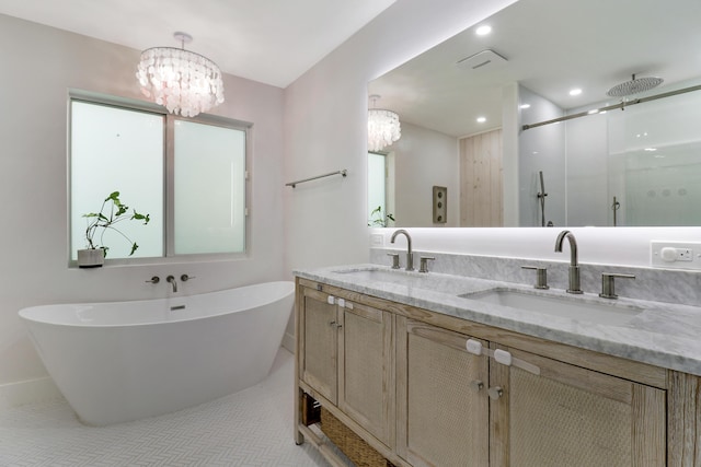 bathroom with an inviting chandelier, a soaking tub, a shower stall, and a sink