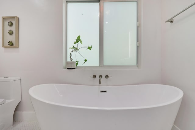 full bath featuring toilet and a freestanding bath