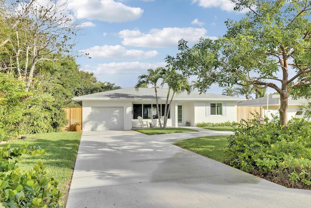 ranch-style home with fence, driveway, stucco siding, a front lawn, and a garage