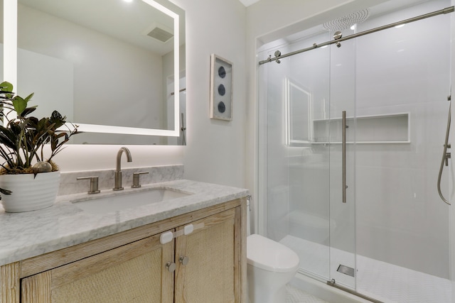 full bathroom featuring vanity, a shower stall, toilet, and visible vents