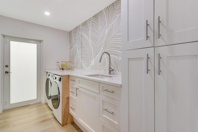 laundry area with light wood finished floors, cabinet space, recessed lighting, separate washer and dryer, and a sink