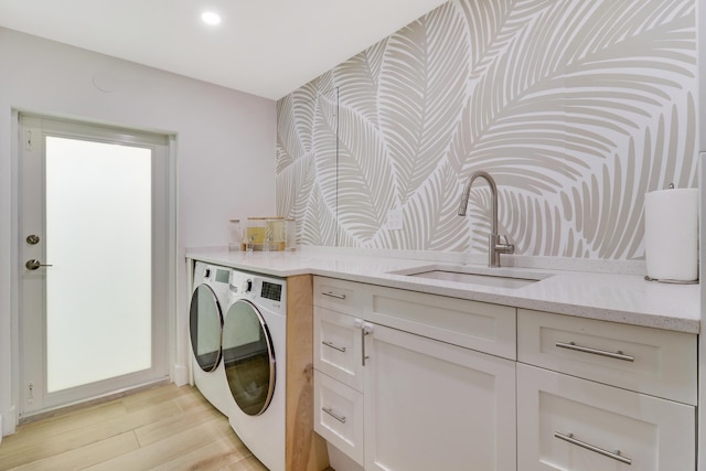 laundry room with light wood-type flooring, recessed lighting, independent washer and dryer, and a sink