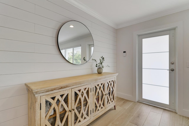 doorway featuring baseboards, light wood-type flooring, and ornamental molding