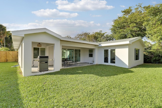 rear view of property with a patio area, stucco siding, a yard, and fence