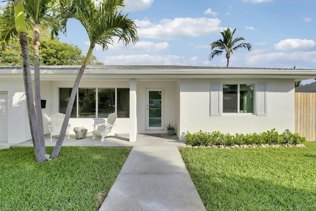 ranch-style home with stucco siding, fence, a front lawn, and a patio area