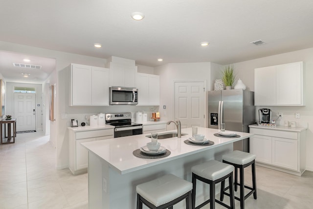 kitchen featuring sink, a breakfast bar area, stainless steel appliances, an island with sink, and white cabinets