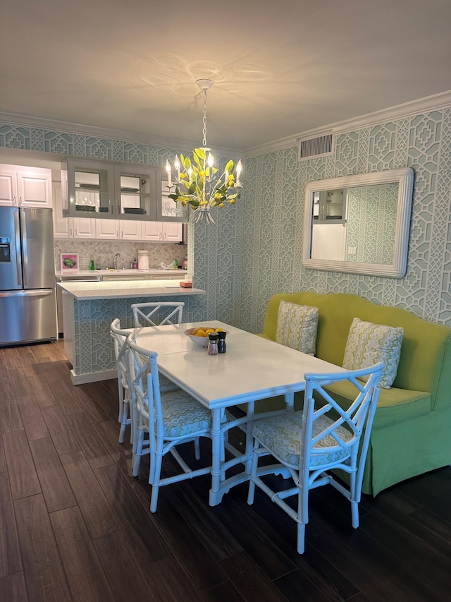 dining room with ornamental molding, dark hardwood / wood-style floors, sink, and a notable chandelier