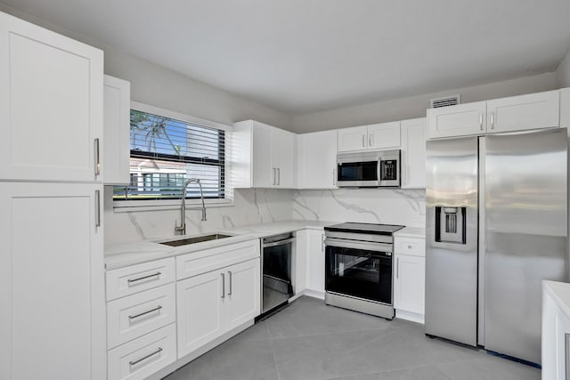 kitchen featuring sink, appliances with stainless steel finishes, light stone counters, tasteful backsplash, and white cabinets