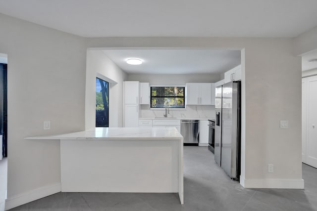 kitchen featuring sink, white cabinetry, appliances with stainless steel finishes, kitchen peninsula, and backsplash