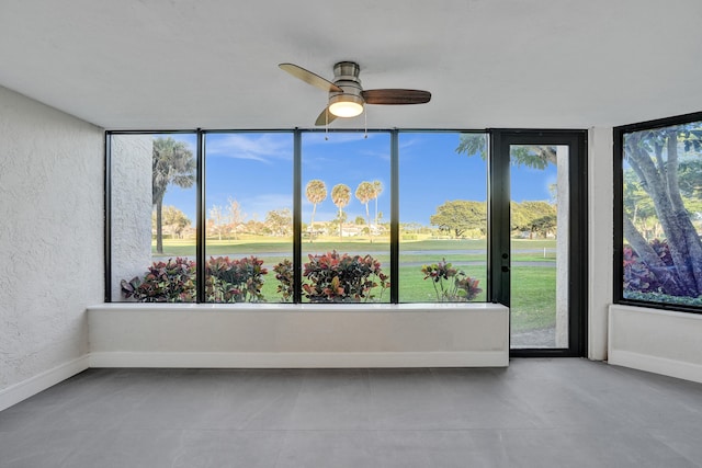 unfurnished sunroom with ceiling fan