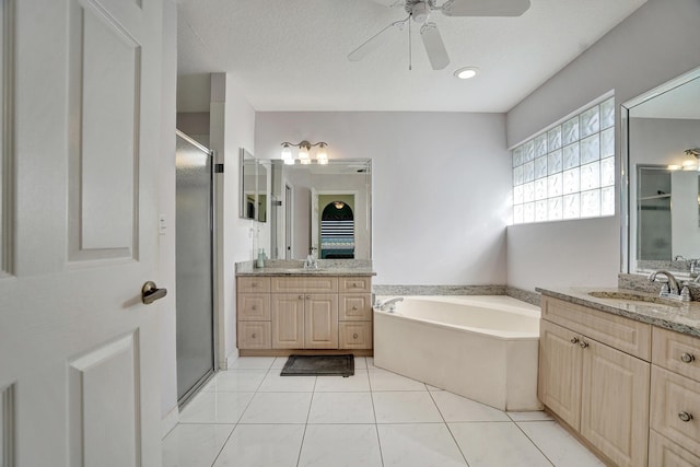 bathroom with independent shower and bath, tile patterned flooring, vanity, ceiling fan, and a textured ceiling