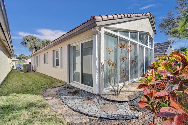 view of side of property featuring a lawn and central air condition unit