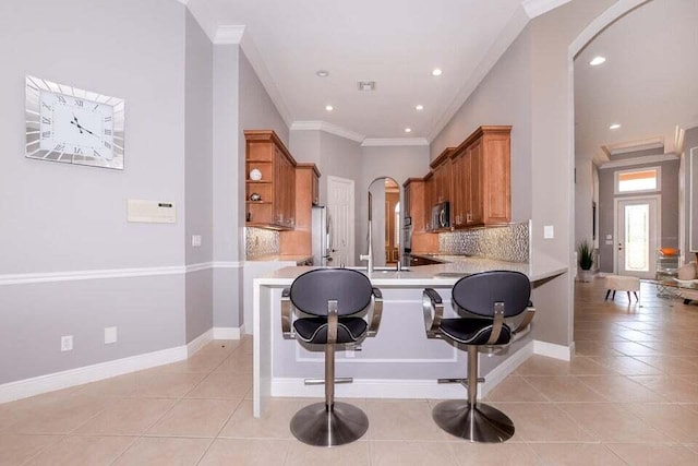 9895 SW Nuova Way, Port Saint Lucie, FL 34986 - kitchen with ornamental molding, a kitchen breakfast bar, kitchen peninsula, and light tile patterned flooring