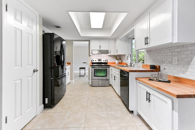 kitchen featuring under cabinet range hood, backsplash, a sink, butcher block counters, and black appliances