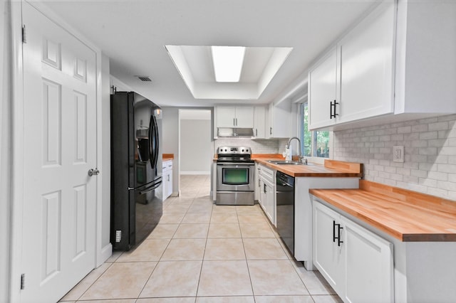 kitchen with wood counters, white cabinetry, sink, light tile patterned floors, and black appliances