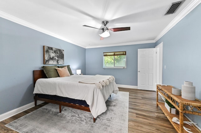 bedroom featuring wood finished floors, visible vents, a ceiling fan, ornamental molding, and baseboards