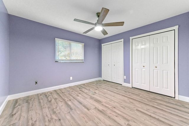 unfurnished bedroom with multiple closets, ceiling fan, and light hardwood / wood-style floors