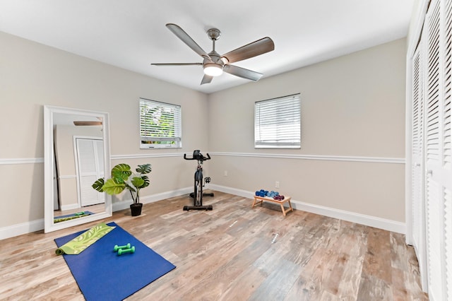exercise area featuring baseboards, wood finished floors, and ceiling fan