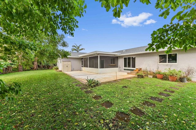 back of property featuring a shingled roof, a yard, stucco siding, a patio area, and a sunroom
