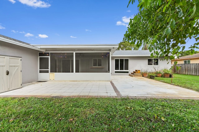 rear view of house featuring a yard, a sunroom, and a patio area