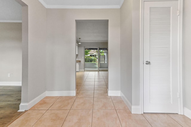 hallway with ornamental molding and light tile patterned floors