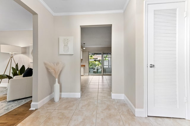 corridor featuring crown molding, baseboards, and light tile patterned floors