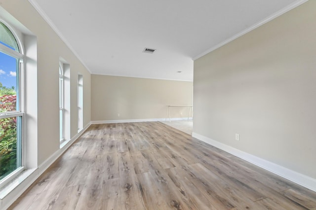 spare room featuring ornamental molding and light hardwood / wood-style flooring