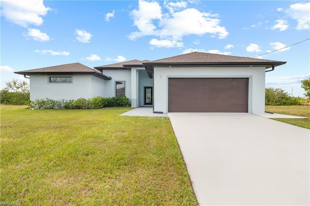 prairie-style home featuring concrete driveway, an attached garage, a front lawn, and stucco siding