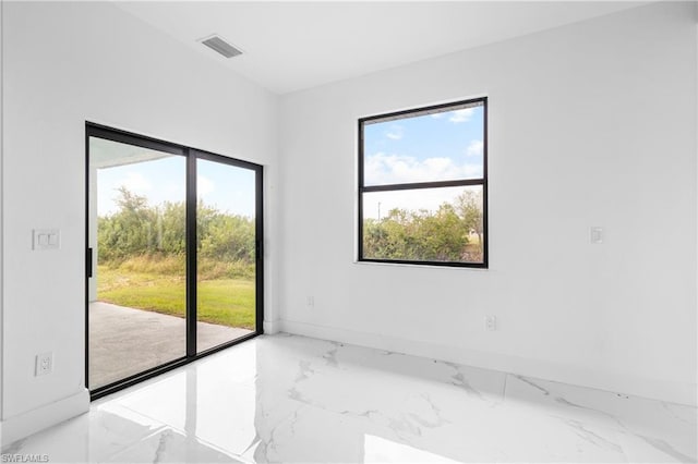 empty room featuring a wealth of natural light, marble finish floor, visible vents, and baseboards