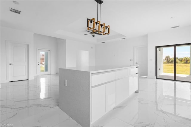 interior space featuring a chandelier, a tray ceiling, marble finish floor, and visible vents